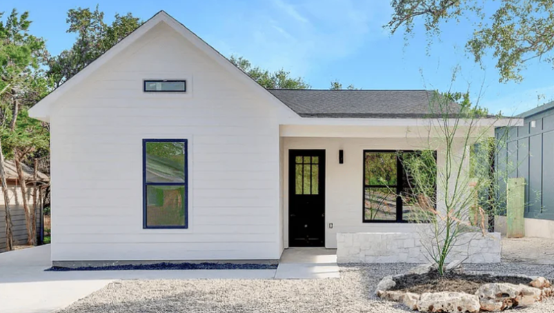 white beautiful, simple house with black front door and rock landscaping